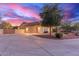 Beautiful home featuring a spacious driveway, three-car garage, and desert landscaping under a colorful twilight sky at 13007 W Tuckey Ct, Glendale, AZ 85307