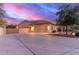 Beautiful home featuring a spacious driveway, three-car garage, and desert landscaping under a colorful twilight sky at 13007 W Tuckey Ct, Glendale, AZ 85307
