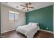 Bedroom with wood floors, a ceiling fan, natural light from window, and a vibrant accent wall at 13545 W Caribbean Ln, Surprise, AZ 85379