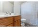 Clean bathroom featuring wood cabinet, white sink, toilet, and shower with curtain at 1361 W Roosevelt Ave, Coolidge, AZ 85128