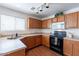 Well-lit kitchen featuring wooden cabinetry, a double basin sink, black appliances and modern track lighting at 1361 W Roosevelt Ave, Coolidge, AZ 85128