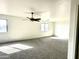 Bright and airy living room featuring neutral carpeting and a ceiling fan at 1492 S 218Th Ln, Buckeye, AZ 85326