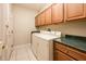 Bright laundry room with tile floor, a utility sink, washer, dryer and wood cabinets at 17218 W Mahogany Way, Surprise, AZ 85387