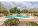 Sparkling pool surrounded by lush greenery, a rock feature, and a well-maintained patio area at 17218 W Mahogany Way, Surprise, AZ 85387