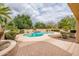 Well-manicured backyard featuring a sparkling pool, lush landscaping, and a charming brick patio at 17218 W Mahogany Way, Surprise, AZ 85387