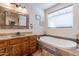 Bright bathroom featuring a soaking tub, granite countertops, and a window with blinds at 2349 W Skyline Ln, San Tan Valley, AZ 85144