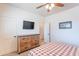 Bedroom with plaid bedding, ceiling fan, dresser, and neutral color palette at 2349 W Skyline Ln, San Tan Valley, AZ 85144