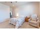 A bright bedroom features a ceiling fan, a comfortable armchair, and a view of the door at 2349 W Skyline Ln, San Tan Valley, AZ 85144