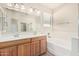 Bright bathroom showcasing double vanity, large mirror, natural light, and a soaking tub for relaxation at 2530 W Gaby Rd, Phoenix, AZ 85041