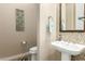 Stylish powder room with a pedestal sink, decorative mirror, and unique wall tiling at 3110 E Cat Balue Dr, Phoenix, AZ 85050