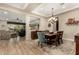 Open-concept dining area with wood-look tile and a view of the adjacent living room with coffered ceiling at 3110 E Cat Balue Dr, Phoenix, AZ 85050