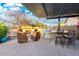 Outdoor kitchen featuring a stone fireplace, built-in grill, and a bar with seating under a stylish pergola at 3110 E Cat Balue Dr, Phoenix, AZ 85050