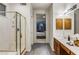 Bathroom featuring a glass shower with gold trim, tile flooring, and a sink with wooden cabinets at 34423 N 68Th Way, Scottsdale, AZ 85266