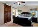 Main bedroom features a dark wood bed frame with a decorative sliding wood door leading to the bathroom at 3519 S 185Th Dr, Goodyear, AZ 85338