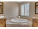 Bright bathroom featuring a soaking tub, dual vanities, and a corner window at 3616 E Kachina Dr, Phoenix, AZ 85044