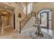 Elegant foyer boasts a grand staircase, detailed ironwork, tile flooring, and an arched doorway at 3616 E Kachina Dr, Phoenix, AZ 85044