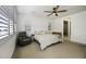 Spacious bedroom features a ceiling fan, shuttered windows, a cozy armchair, and an ensuite bathroom at 40481 W Desert Fairways Dr, Maricopa, AZ 85138