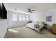 Bright bedroom with carpet flooring, fan, white walls, plantation shutters, and TV at 40481 W Desert Fairways Dr, Maricopa, AZ 85138