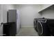 Bright laundry area featuring a modern washer and dryer, shelving and a compact refrigerator at 40481 W Desert Fairways Dr, Maricopa, AZ 85138