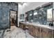 Luxurious bathroom featuring marble countertops, double sinks, vanity seating, marble walls and floors, and a walk-in closet at 42105 N Golf Crest Rd, Anthem, AZ 85086