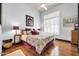 Bright bedroom featuring hardwood floors, a large window with shutters, neutral walls, and comfortable furnishings at 42105 N Golf Crest Rd, Anthem, AZ 85086