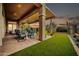 Beautiful covered patio with dining area overlooking artificial turf and desert landscaping at dusk at 42105 N Golf Crest Rd, Anthem, AZ 85086