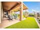 Outdoor covered patio featuring a dining set and a view of the artificial turf and desert landscaping at 42105 N Golf Crest Rd, Anthem, AZ 85086