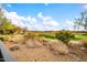 Beautiful golf course view from the backyard with green grass and lush desert plants in foreground at 42105 N Golf Crest Rd, Anthem, AZ 85086