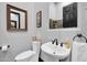 Stylish half bathroom featuring a pedestal sink, framed mirror, and dark wood accents at 42105 N Golf Crest Rd, Anthem, AZ 85086