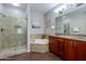 Bathroom with double vanity, shower, and tub. Wood cabinet and dark floors at 5350 E Deer Valley Dr # 4408, Phoenix, AZ 85054