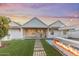 Spacious backyard at dusk featuring a pool, outdoor kitchen, fire feature, and brick pavers at 542 E Hayward Ave, Phoenix, AZ 85020