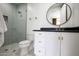 Modern bathroom showcasing a glass enclosed shower with grey tile, a black countertop and a round mirror at 542 E Hayward Ave, Phoenix, AZ 85020