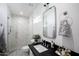 Bright bathroom featuring a glass shower with beige tile, a vanity with a black countertop and decorative towels at 542 E Hayward Ave, Phoenix, AZ 85020