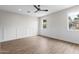 Bright bedroom featuring wood-look flooring, paneled walls, and natural light from the large windows at 6719 N 10Th Pl, Phoenix, AZ 85014