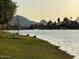 Relaxing lakeside view featuring a bench, lush grass, and peaceful water with mountains in the background at 8653 E Royal Palm Rd # 1006, Scottsdale, AZ 85258