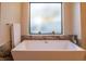 Bright bathroom with square tub, marble accents, and frosted window for natural light and privacy at 9440 N 57Th St, Paradise Valley, AZ 85253