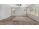 A spacious carpeted bedroom featuring a ceiling fan and natural light from two windows at 9545 W Williams St, Tolleson, AZ 85353