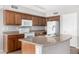 Functional kitchen featuring wood cabinets, white appliances, and granite countertops with an island and sink at 9545 W Williams St, Tolleson, AZ 85353