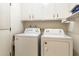 Efficient laundry room with washer, dryer, and overhead cabinets for storage solutions at 10611 W Camelot Cir, Sun City, AZ 85351