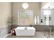 Bright bathroom featuring a freestanding tub, glass block window, and a modern chandelier at 11256 E Palomino Rd, Scottsdale, AZ 85259