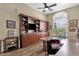 A home office featuring a built-in wooden bookcase, a ceiling fan, and a large window providing ample natural light at 11256 E Palomino Rd, Scottsdale, AZ 85259