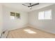 A bedroom with wood-look floors, two windows, a ceiling fan, and white painted walls at 113 W Rawhide Ave, Gilbert, AZ 85233