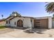 Street view of a single-story stucco home featuring an arched entryway, detached garage, and low-maintenance landscaping at 113 W Rawhide Ave, Gilbert, AZ 85233