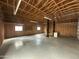 Spacious interior of a large garage featuring unfinished walls, two windows, lift system and concrete flooring at 113 W Rawhide Ave, Gilbert, AZ 85233