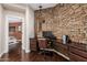 Cozy home office featuring a stone accent wall, dark wood floors, and a built-in desk at 12129 W Desert Mirage Dr, Peoria, AZ 85383