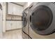 Modern laundry room with white cabinets, granite countertop and tile floors features side-by-side washer and dryer at 13729 E Rancho Laredo Dr, Scottsdale, AZ 85262