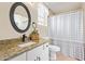 Well-lit bathroom featuring granite countertops, neutral paint, framed mirror and tub with patterned shower curtain at 14609 W Marcus Dr, Surprise, AZ 85374