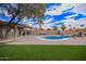 Backyard pool with lounge chairs, lush turf, and a covered patio with a hot tub in a desert landscape at 14609 W Marcus Dr, Surprise, AZ 85374