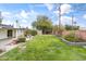 Large backyard featuring a green lawn, mature trees, garden beds, and a covered patio at 1509 W Tuckey Ln, Phoenix, AZ 85015