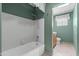 Well-lit bathroom features a tub with white tiling and green painted walls at 1509 W Tuckey Ln, Phoenix, AZ 85015